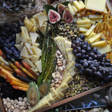 Cheese board with nuts, grapes, and asparagus